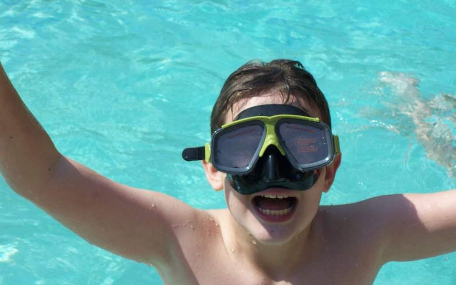 kid by a pool wearing scuba mask