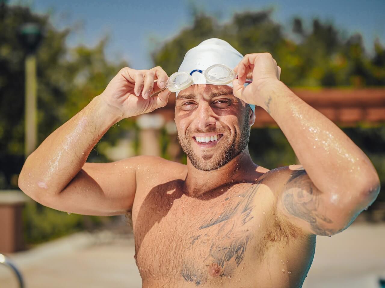 tattooed man wearing swim cap and goggles