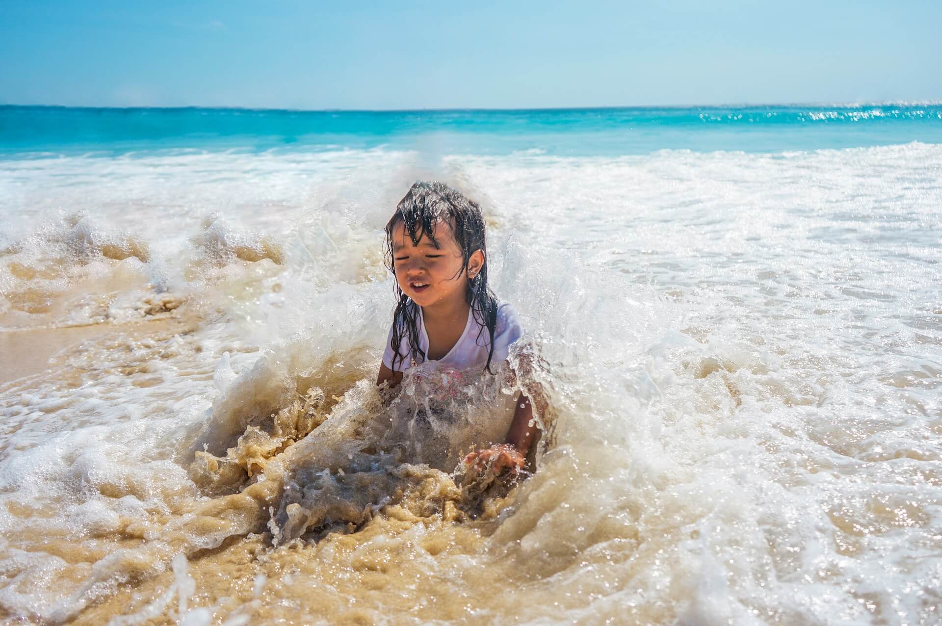 child splashed by ocean