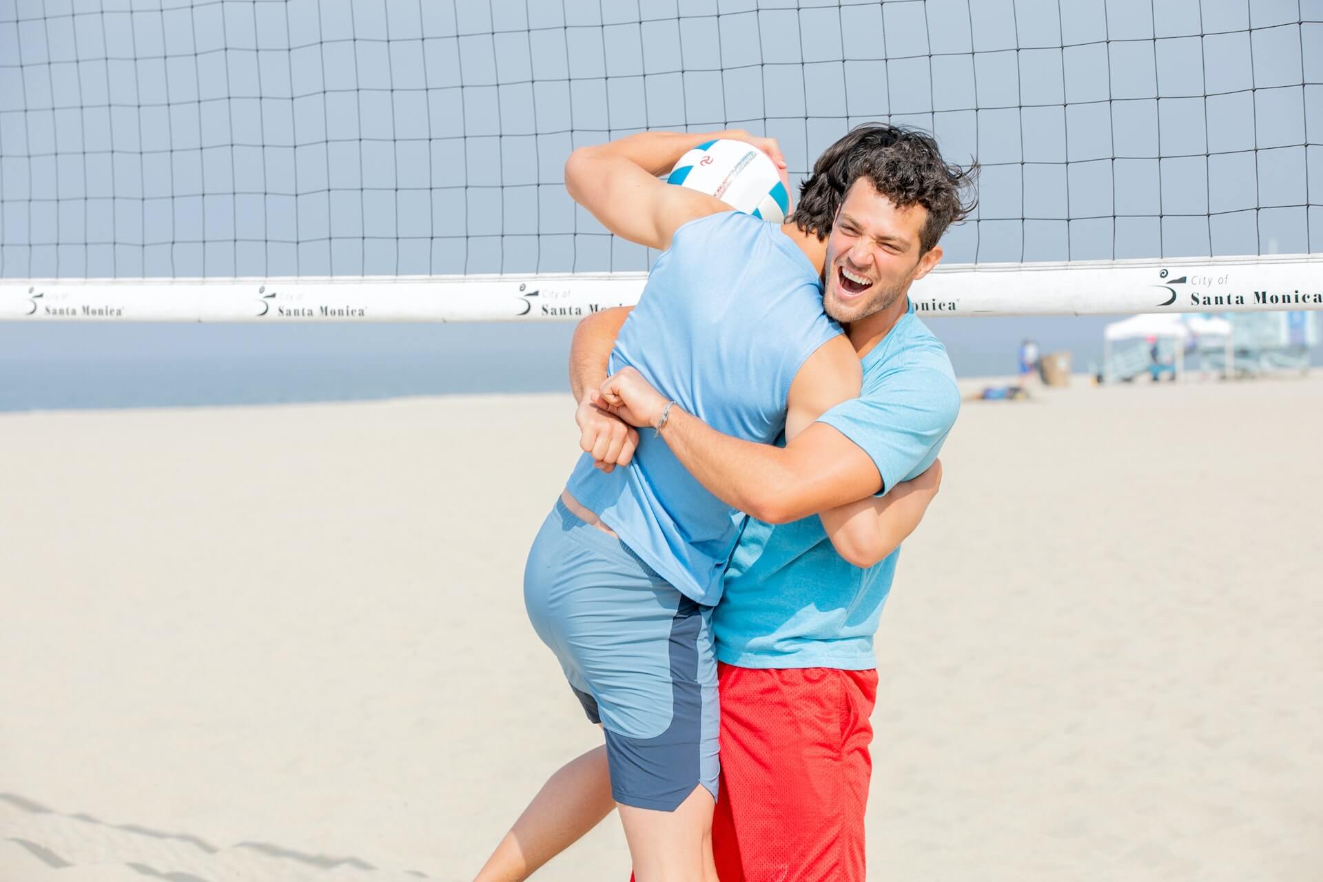 men hugging while playing volleyball