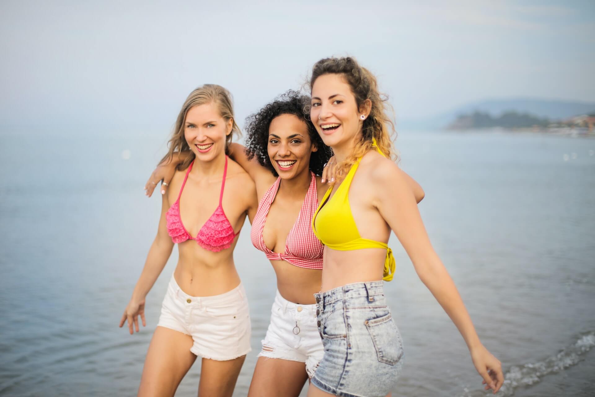 three girls in swimwear by the beach