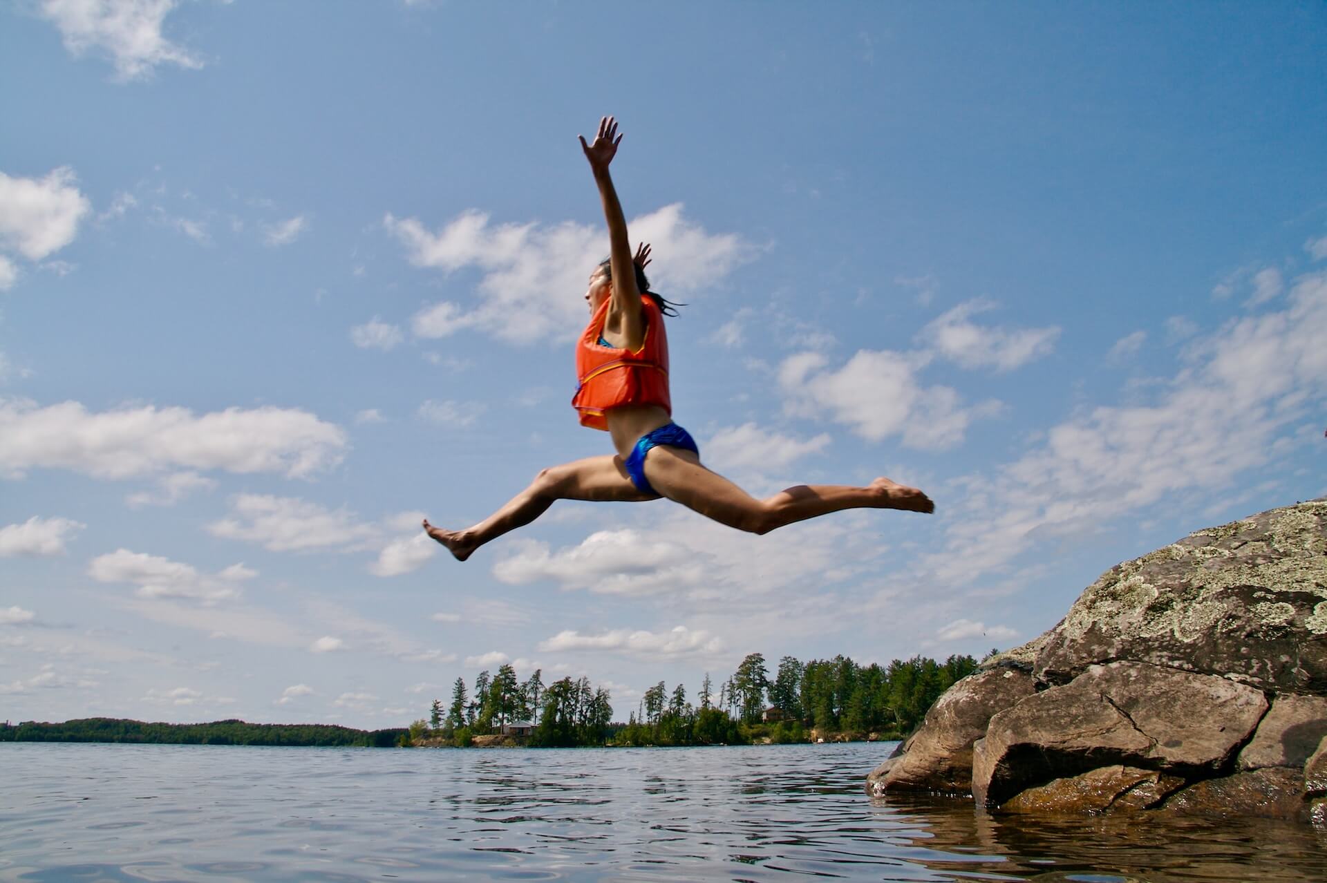 woman with life vest jumping into lake